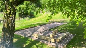 eine Steinbank im Schatten eines Baumes in der Unterkunft Domaine du Chant de la Planche - SPA - Hautes Vosges in Saulxures-sur-Moselotte + 2 Fotos