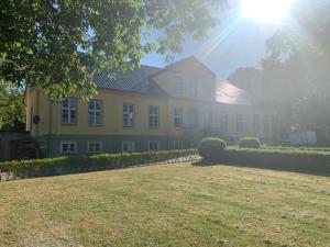 a large yellow house with the sun shining behind it at Gutshausferien im Ostseehinterland 