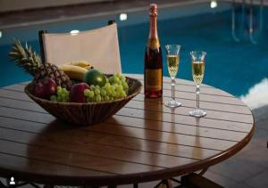 Queen Boutique Suites Preveza في بريفيزا: طاولة مع وعاء من الفاكهة وكأسين من النبيذ