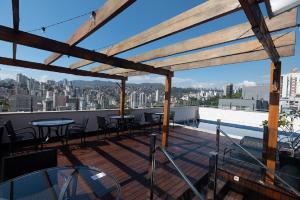 a rooftop deck with tables and chairs and a view of the city at eSuites Virgínia Luxemburgo in Belo Horizonte