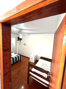 una habitación con cama y una habitación con banco en Pousada do Genesio, en Petrópolis