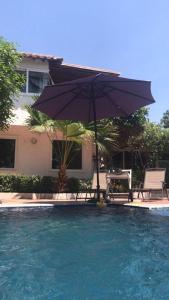 un parasol et une chaise à côté de la piscine dans l'établissement El Canto del Mar, à Santa Marta