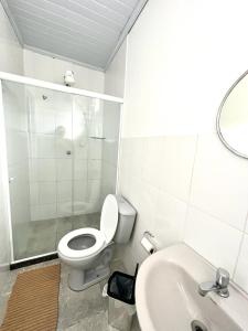 La salle de bains blanche est pourvue de toilettes et d'un lavabo. dans l'établissement Pousada do Genesio, à Petrópolis