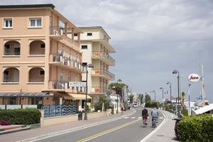 Dos personas en bicicleta por una calle junto a un edificio en Hotel Euro, en Bellaria-Igea Marina