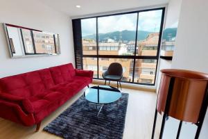 - un salon avec un canapé rouge et une table en verre dans l'établissement Apartamento KANNA-402, à Bogotá
