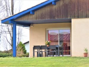 una casa con techo azul, mesa y sillas en Le saoutot, en Saint-Jean-de-Marsacq