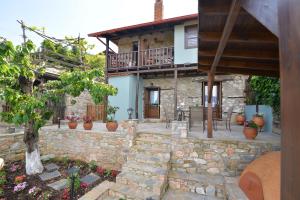 een huis met een stenen muur en een patio bij To Patriko Mas Guesthouse-1 in Palaios Panteleimon