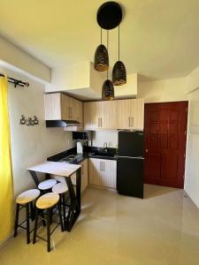 a kitchen with a black refrigerator and a table with stools at Cozy almond drive condo in cebu in Talisay