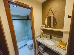 a bathroom with a sink and a toilet and a mirror at Village aconchegante em Mucugê in Mucugê +23 photos