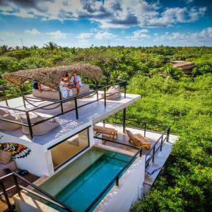 a villa with a swimming pool and two people sitting on a house at Suites Tulum in Tulum