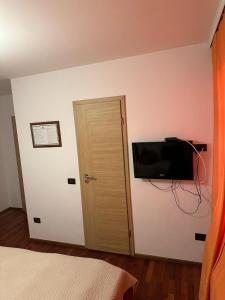 a bedroom with a door and a television on the wall at Apartments Prizreni in Prizren