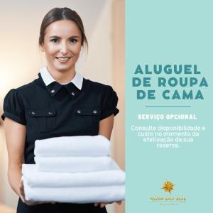 a woman holding a stack of white towels at Vila Luna in Bombinhas