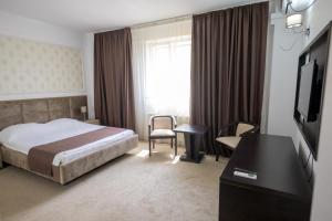 a hotel room with a bed and a desk and a television at Hotel Maryiotis in Constanţa