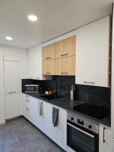 uma cozinha com armários brancos e bancadas pretas em Pérola dos Salgados em Guia