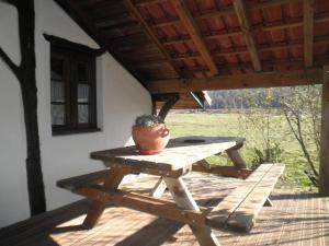 una mesa de picnic de madera con una olla en el porche en Petit tachette, en Herm
