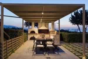 un patio con mesa y sillas bajo un techo en Lux Villa Mia with Heated Pool, 2km to Beach & Childrens Area! en Mikro Metochi