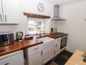 una cocina con fregadero y un reloj en la pared en The Coach House, en Haverfordwest