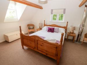 um quarto com uma grande cama de madeira com almofadas roxas em The Coach House em Haverfordwest