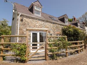 an old stone cottage with a wooden gate and fence at The Coach House in Haverfordwest