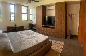 a bedroom with a bed and a flat screen tv at Moderno y Comodo Loft Asoluta in Mérida