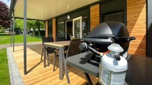 un grill su una terrazza con tavolo e sedie di Mobilhome a Steindorf am Ossiacher See