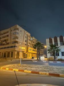 an empty street in front of a building with palm trees at Eden Park, in Algeria by the beach. in Oran