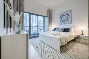 a white bedroom with a large bed and a large window at Luxury 1 Bedroom With Sea View in Dubai