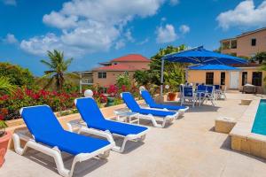 eine Reihe blauer Liegestühle und ein Pool in der Unterkunft Villa by the sea in Five Islands Village