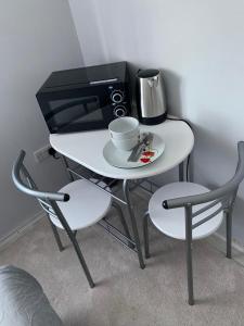 uma pequena mesa branca com um micro-ondas e comodidades para preparar café em Double room bentilee em Bucknall