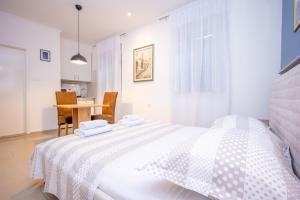 a white bedroom with a bed and a table at Apartment Bosanska in Split
