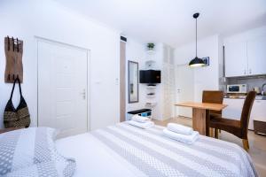 a white bedroom with a bed and a kitchen at Apartment Bosanska in Split