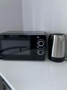 a black microwave sitting on a counter with a coffee pot at Double room bentilee in Bucknall