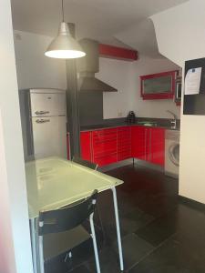 eine Küche mit roten Schränken sowie einem Tisch und Stühlen in der Unterkunft Zoe in Vilamós