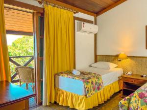 a bedroom with a bed and a window with a balcony at Hotel Nacional Inn Ubatuba - Praia das Toninhas in Ubatuba