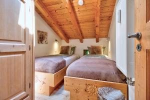 two beds in a room with wooden ceilings at Gipfelglück in Reit im Winkl