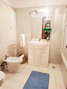 a white bathroom with a sink and a toilet at Golden wave in Ericeira
