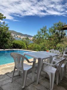una mesa blanca y sillas junto a una piscina en casa con vista y bajada al lago en Villa Carlos Paz