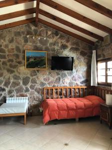 ein Schlafzimmer mit einem roten Bett in einer Steinmauer in der Unterkunft casa con vista y bajada al lago in Villa Carlos Paz