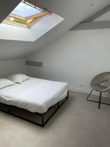 a bedroom with a bed and a chair and a skylight at Domaine chloé du lac in Montferrat