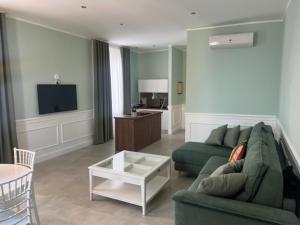 ein Wohnzimmer mit einem grünen Sofa und einem TV in der Unterkunft Chiostro San Francesco - Casa di Ospitalità Religio sa in Neapel