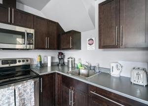 a kitchen with wooden cabinets and a sink and a microwave at Separate Suite in Prestigious Linley Valley in Nanaimo