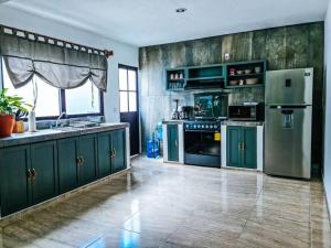 uma grande cozinha com armários verdes e electrodomésticos em Casa Mágico Bacalar em Bacalar