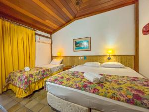 two beds in a room with yellow curtains at Hotel Nacional Inn Ubatuba - Praia das Toninhas in Ubatuba