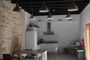 a kitchen with a table and several pendant lights at Lo Molí de Bot in Bot