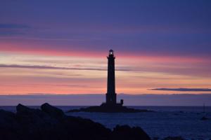 a lighthouse on a island in the ocean at sunset at La Ferme du Raz Blanchard in Auderville