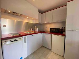 a kitchen with white cabinets and a red counter top at Studio 4pers climatisé accès direct plage in Marseillan