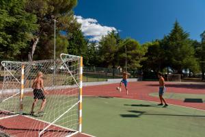 un grupo de hombres jugando al fútbol en una pista de tenis en Koversada Apartments Naturist Park, en Vrsar