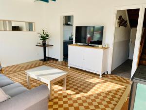 a living room with a couch and a flat screen tv at Le Petit de la Ferme du Raz Blanchard in Auderville