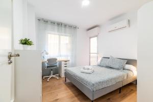a white bedroom with a bed and a desk at Modern Plaza de Toros Apartment with Free Parking in Granada