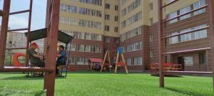 Promyshlennyy的住宿－Новая квартира в столице Казахстана г. Астана，两个人在大楼的操场上玩耍
